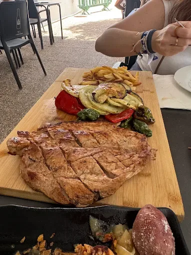 Chuletón a la brasa con parrillada de verduras y papas, sobre tabla